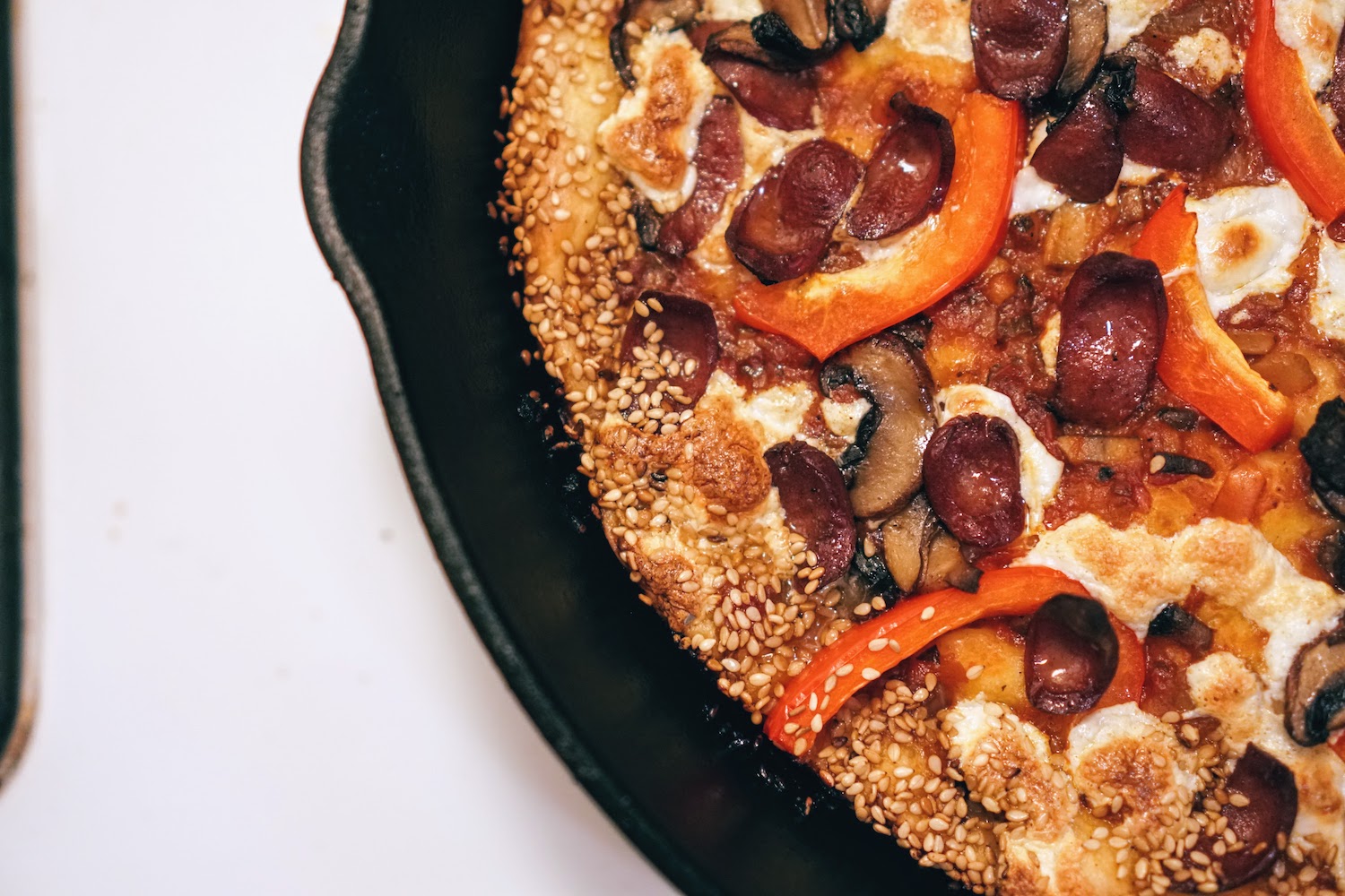 A pizza with sesame seed crust in a cast iron pan
